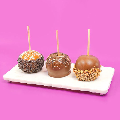 three decorated chocolate dipped caramel apples