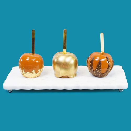 three caramel apples decorated with gold dust, gold leaf, gold sprinkles
