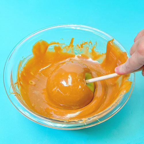 apple being swirled and coated into melted caramel