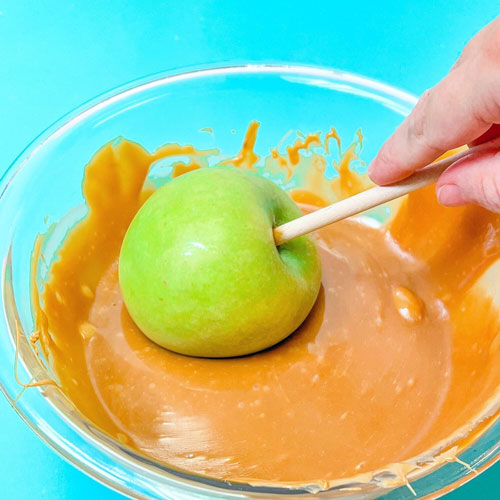 apple being dipped into melted caramel