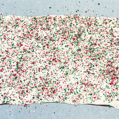 red and green crushed peppermint sprinkled onto melted chocolate for bark