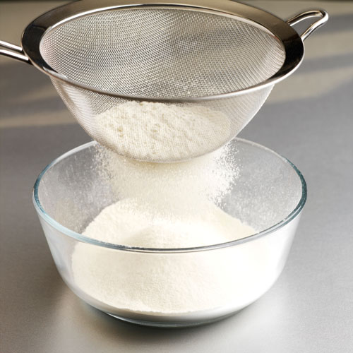 sifting meringue powder into a bowl