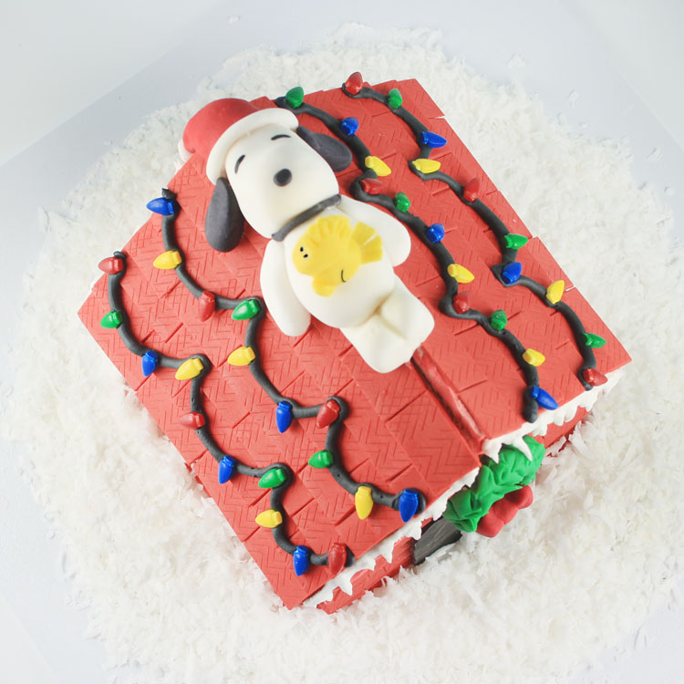 snoopy laying on top of his gingerbread doghouse decorated for christmas