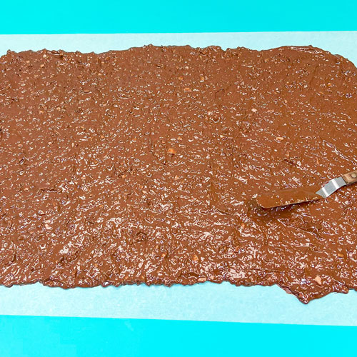 spreading melted chocolate and toffee onto parchment paper