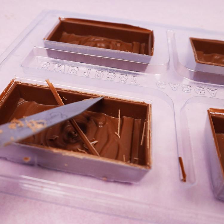 cleaning the edges of the molded chocolate with a knife
