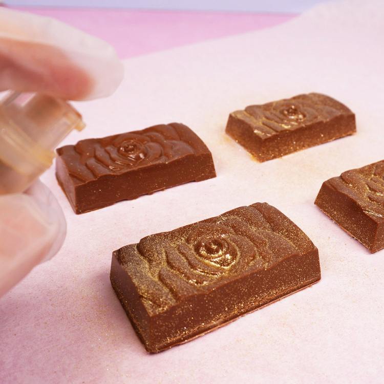 spraying chocolate bars with edible gold glitter