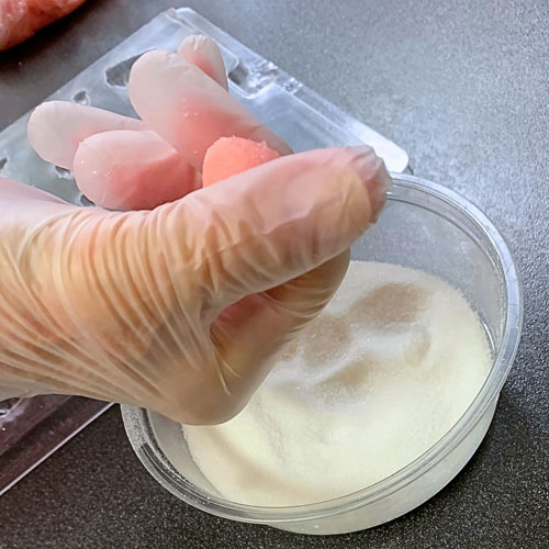rolling homemade buttermint dough into sugar