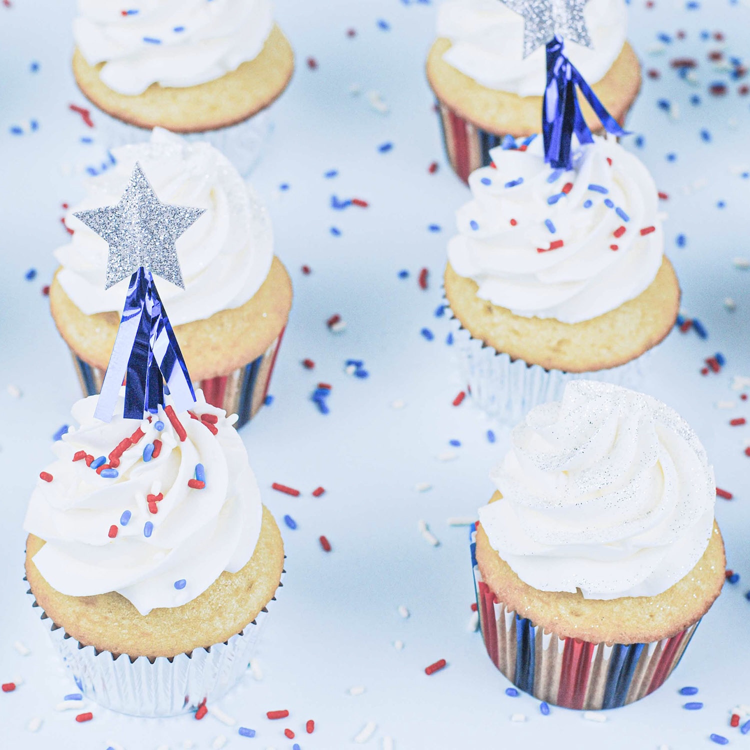  white cake baked in Stars and Stripes Cupcake liners with shooting star picks with a dash of sprinkles and silver sparkly dust.