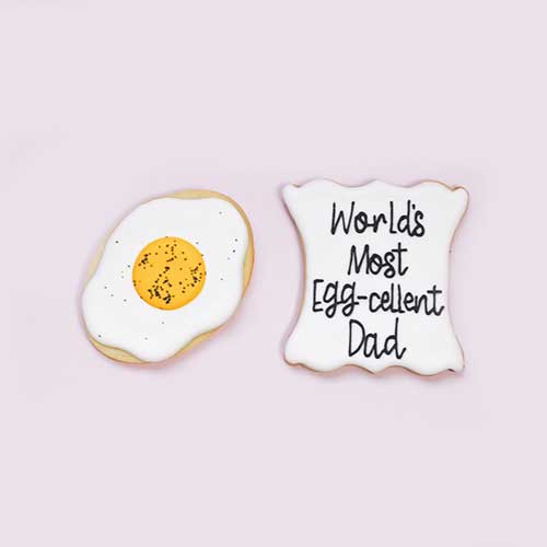 Father's Day Egg-cellent Pun Cookies decorated as fried eggs and a plaque cookie says World's Most Egg-cellent Dad! deocrated in royal icing