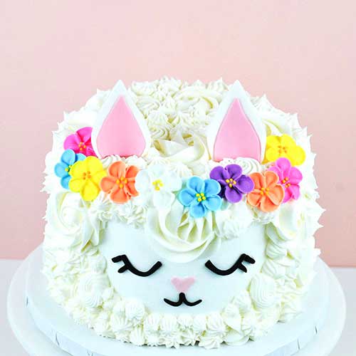 Floral Llama Cake covered with buttercream piped rosettes, stars and swirls, fondant shaped ears and crowned with royal icing flowers.