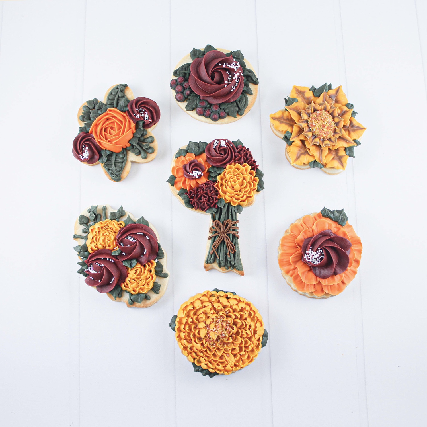 Fall colored buttercream piped flowers on cookies. Rosettes, chrysanthemums, roses, ribbon flowers, sunflowers.