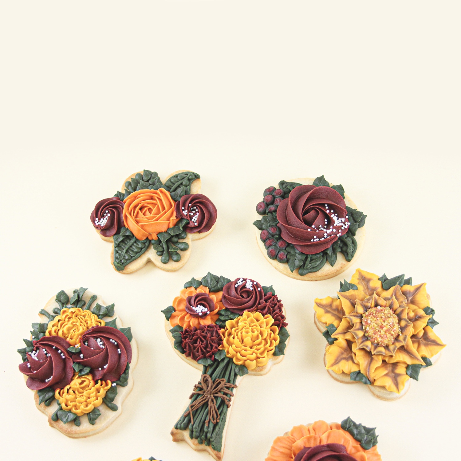 Buttercream flowers piped on cookies in crimson, orange and golden yellow.