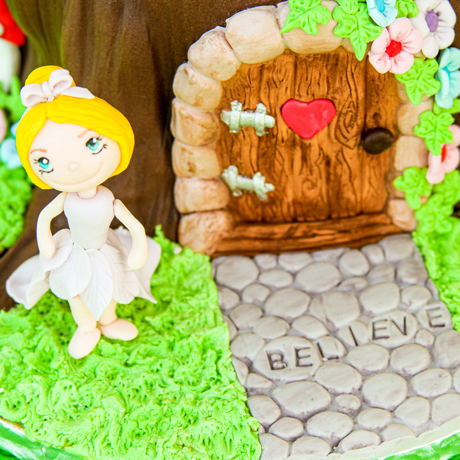 Fairy Scultped in fondant standing at the front door of her tree trunk house.