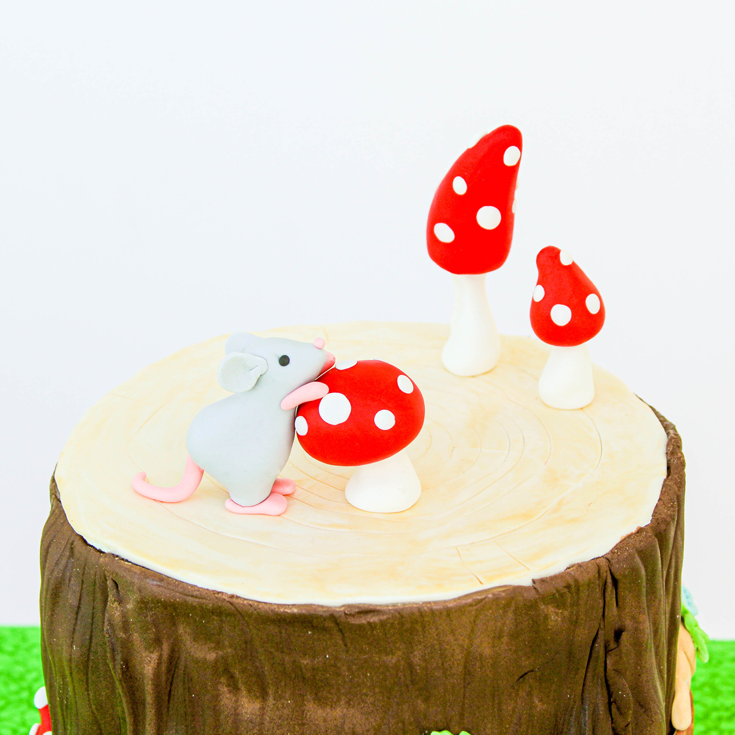 Top of the tree trunk house with a field mouse and 3 red mushrooms covered in white polka dots
