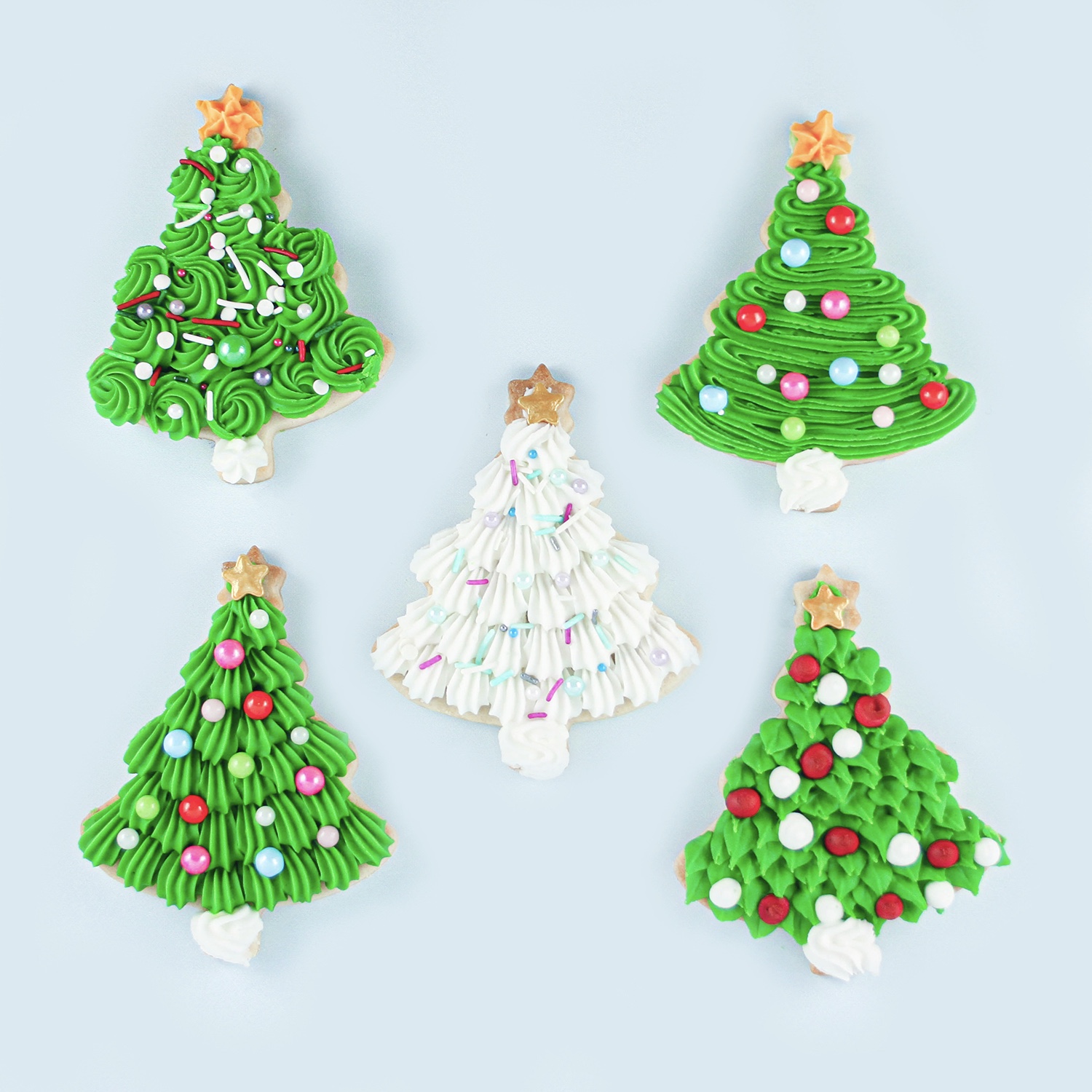 Christmas Tree Sugar Cookies decorated in buttercream in 4 different styles using leaf tip, star tip piping shells, rosettes and zigzags. adorned with sprinkles and a star at the top of the tree