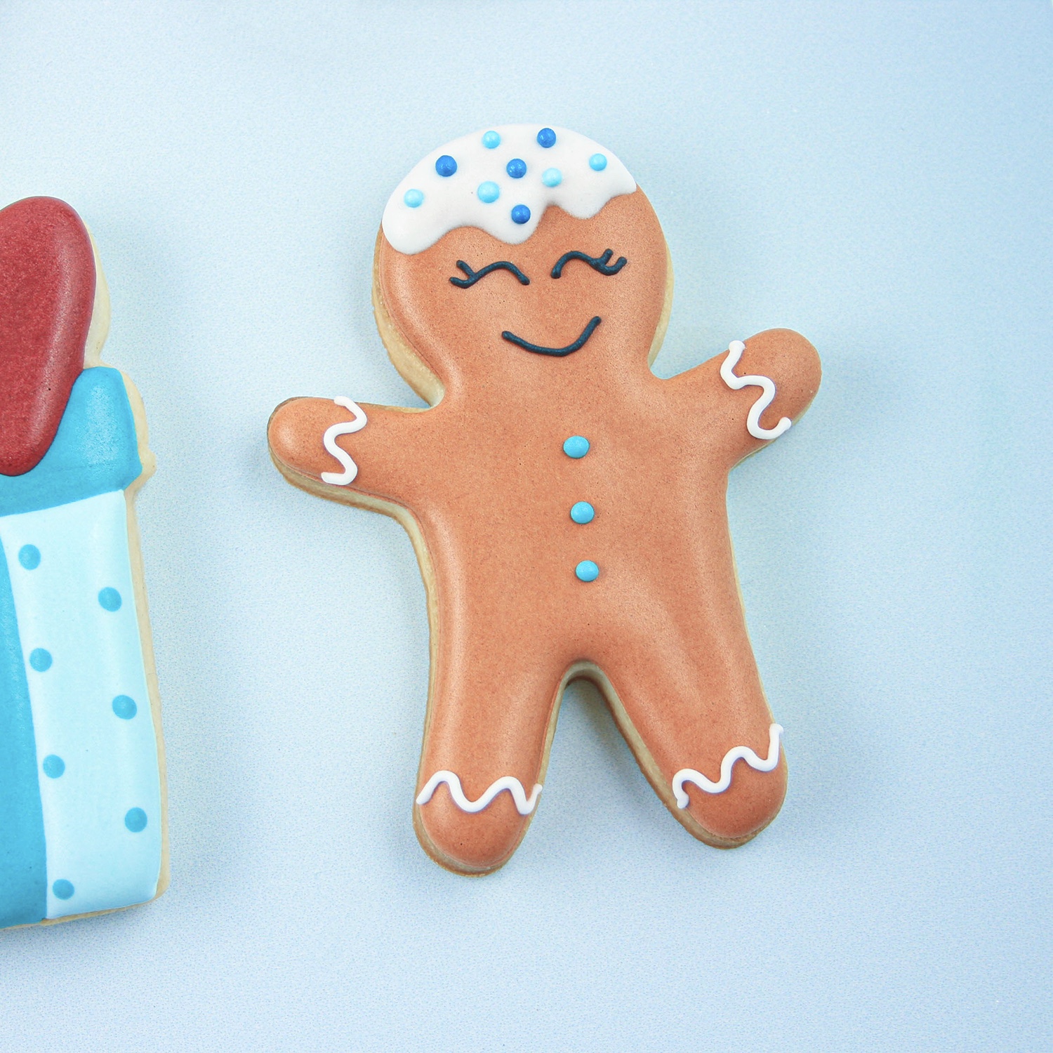 Gingerbread boy decorated with royal icing on his head and blue buttons