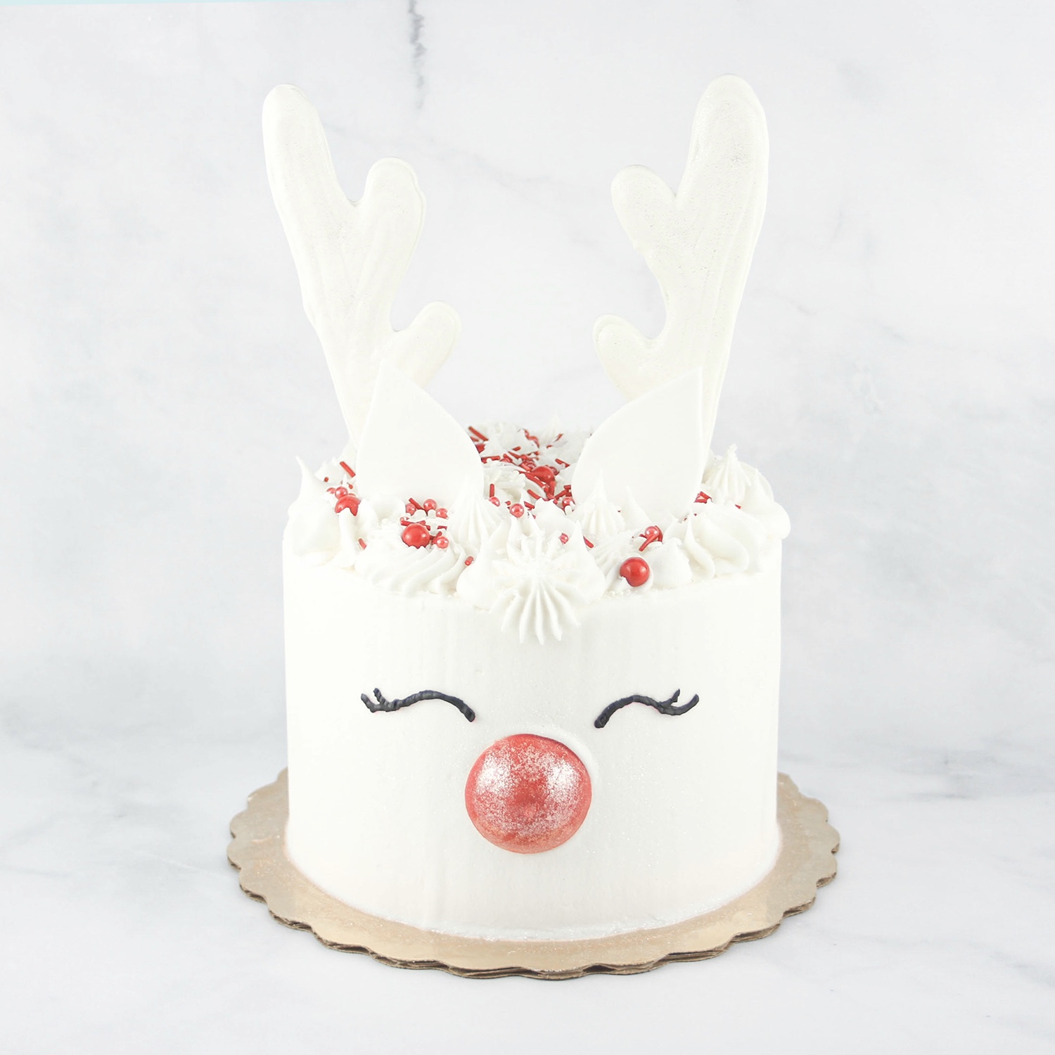 White Reindeer cake with a chocolate rd nose and white chocolate antlers and black buttercream eyelashes