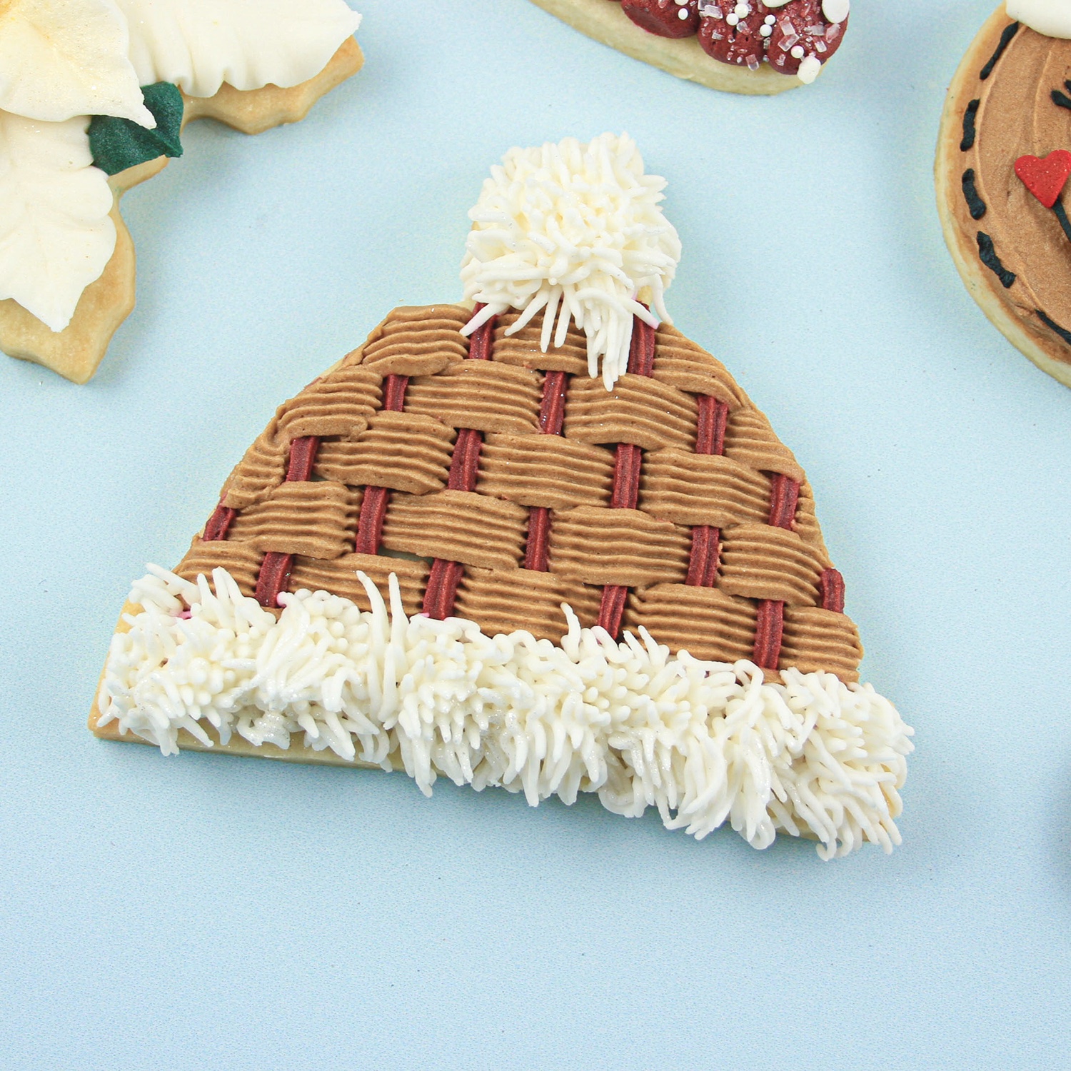 Christmas snow cap piped in brown basketweave and red star tipped buttercream ?with ivory fur brim and pompom.