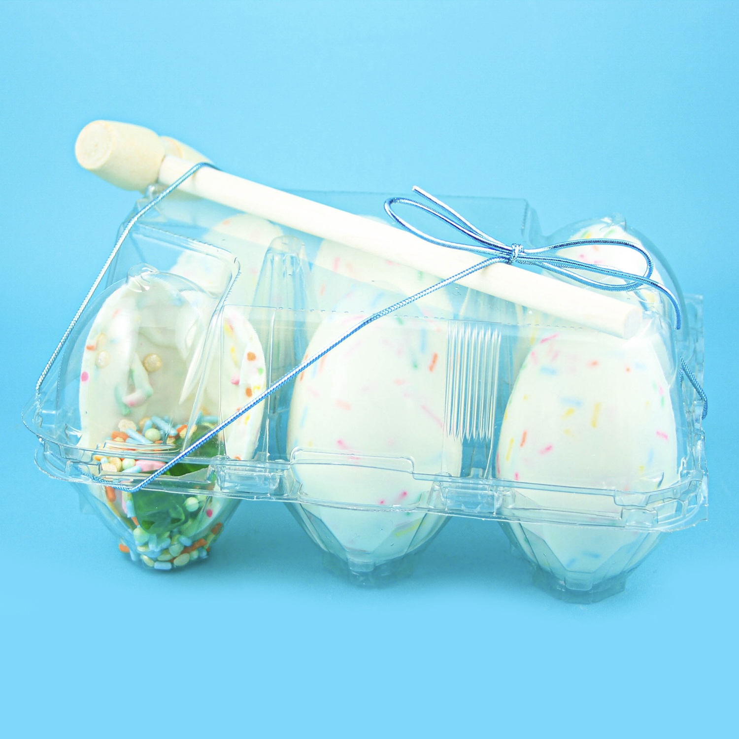 White chocolate breakable eggs packaged in clear egg carton and tied with a blue stretch and wooden hammer