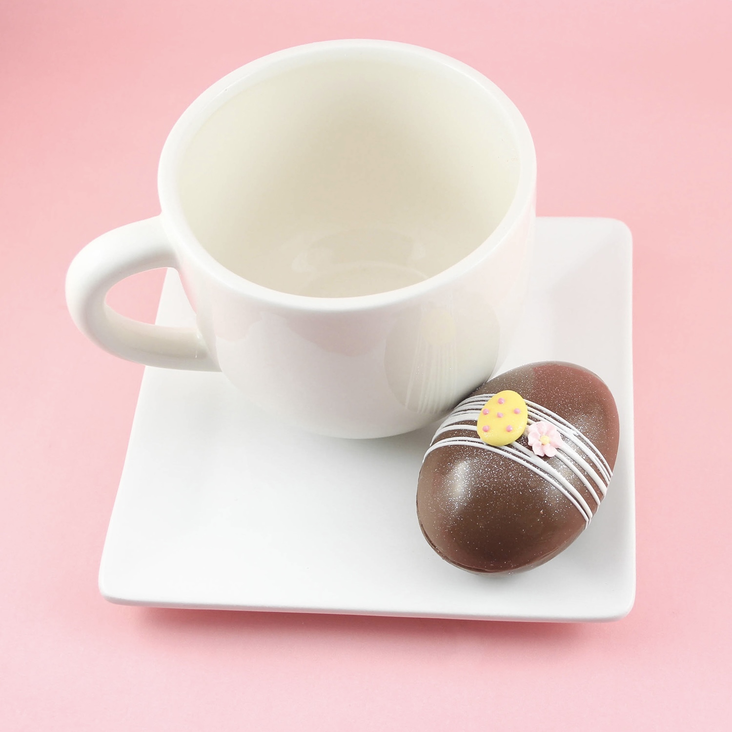 Egg hot chocolate bomb on plate with a mug