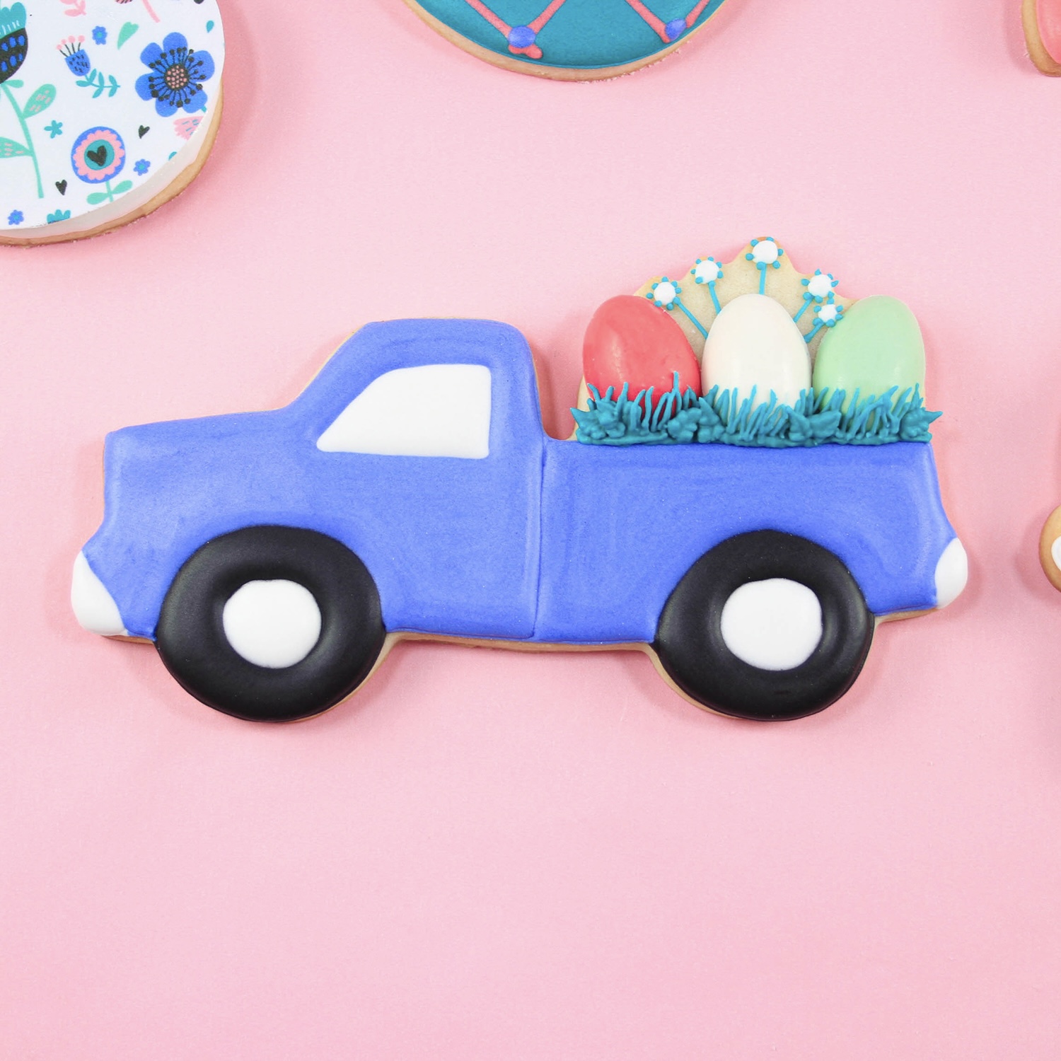 Royal icing decorated purple easter truck hauling chocole molded eggs nestled in blue grass