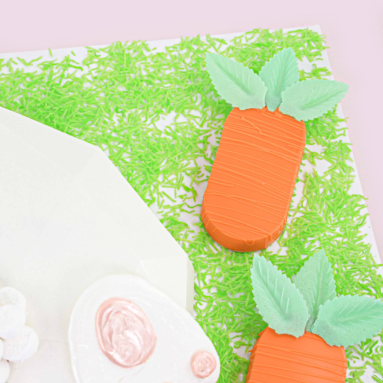 sandwich cookie molded carrot drizzled in orange coating and green wafer paper leaves glued on for carrot stems