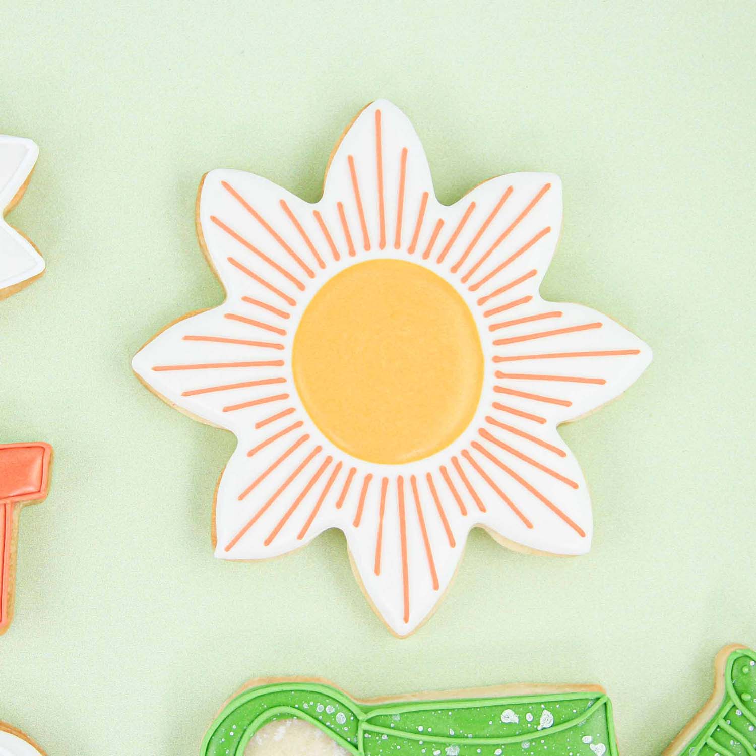 Sunshine Cookie with a white sunflower background and orange rays decorated in royal icing