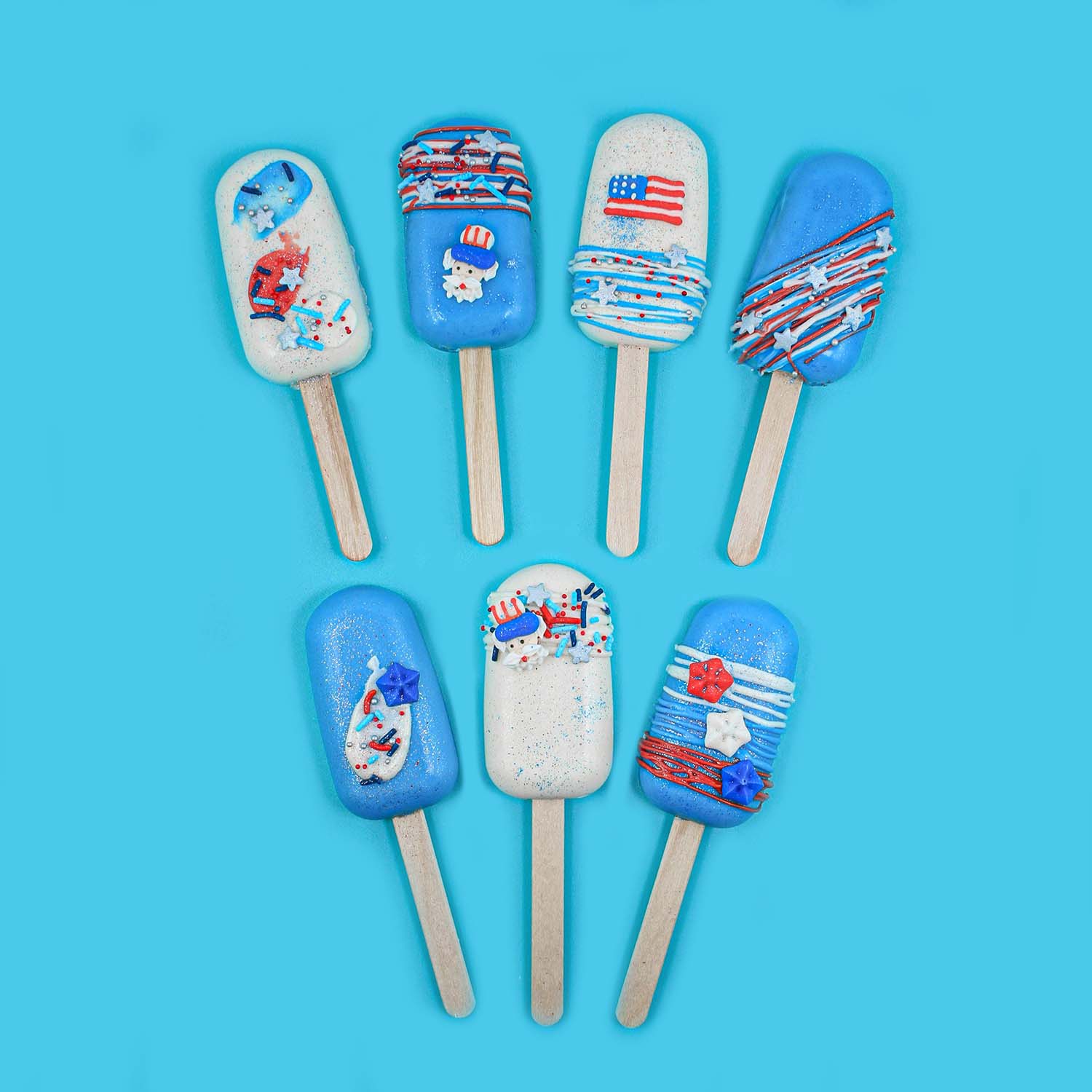 Blue and white cakesicles with red white and blue drizzle and sprinkles