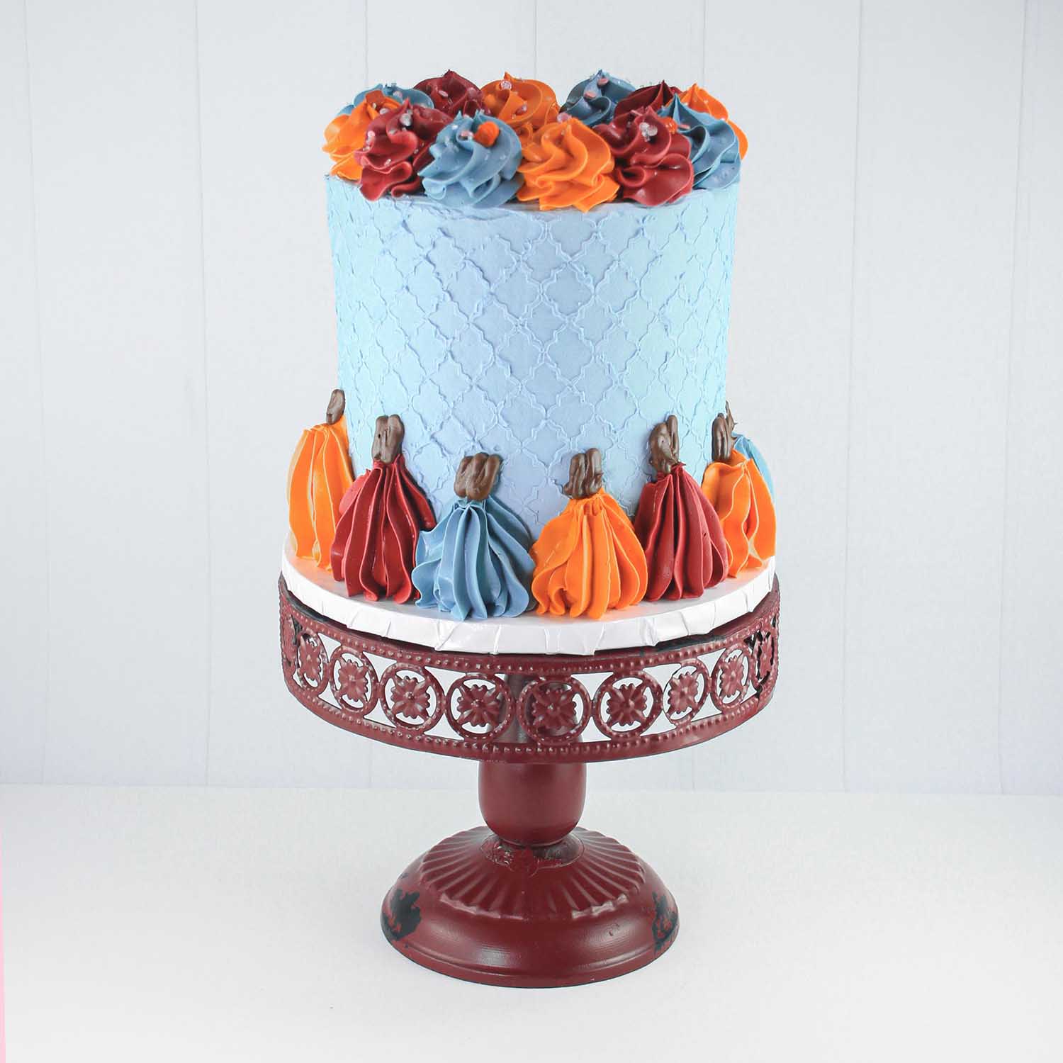 Blue buttercream stenciled cake with a 1M tip piped pumpkin border and adorned swirls on top in burgundy, wedgewood and pumpkin colored buttercream.