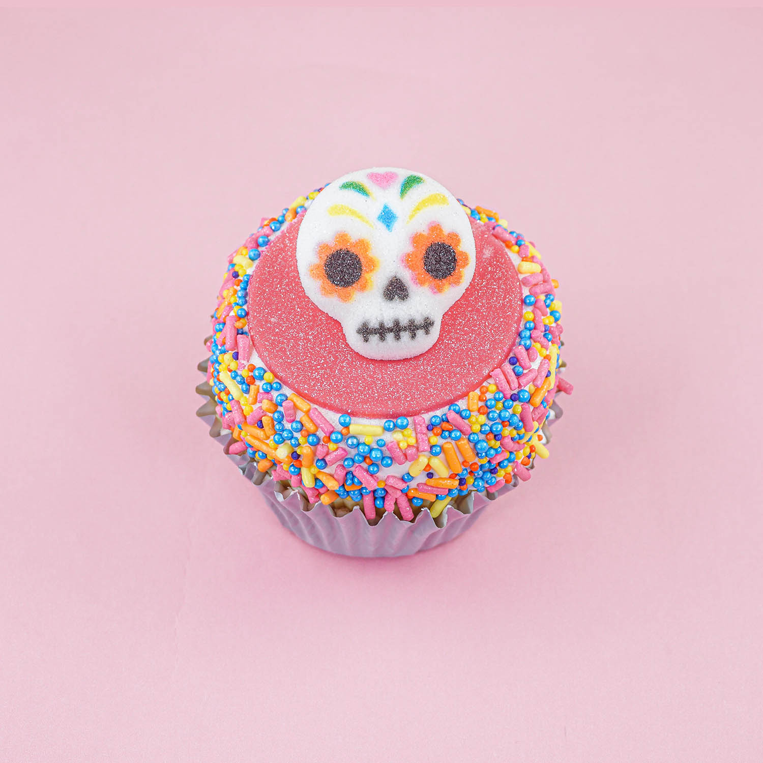 Pink fondant sprinkle cupcake with sugar skull layon