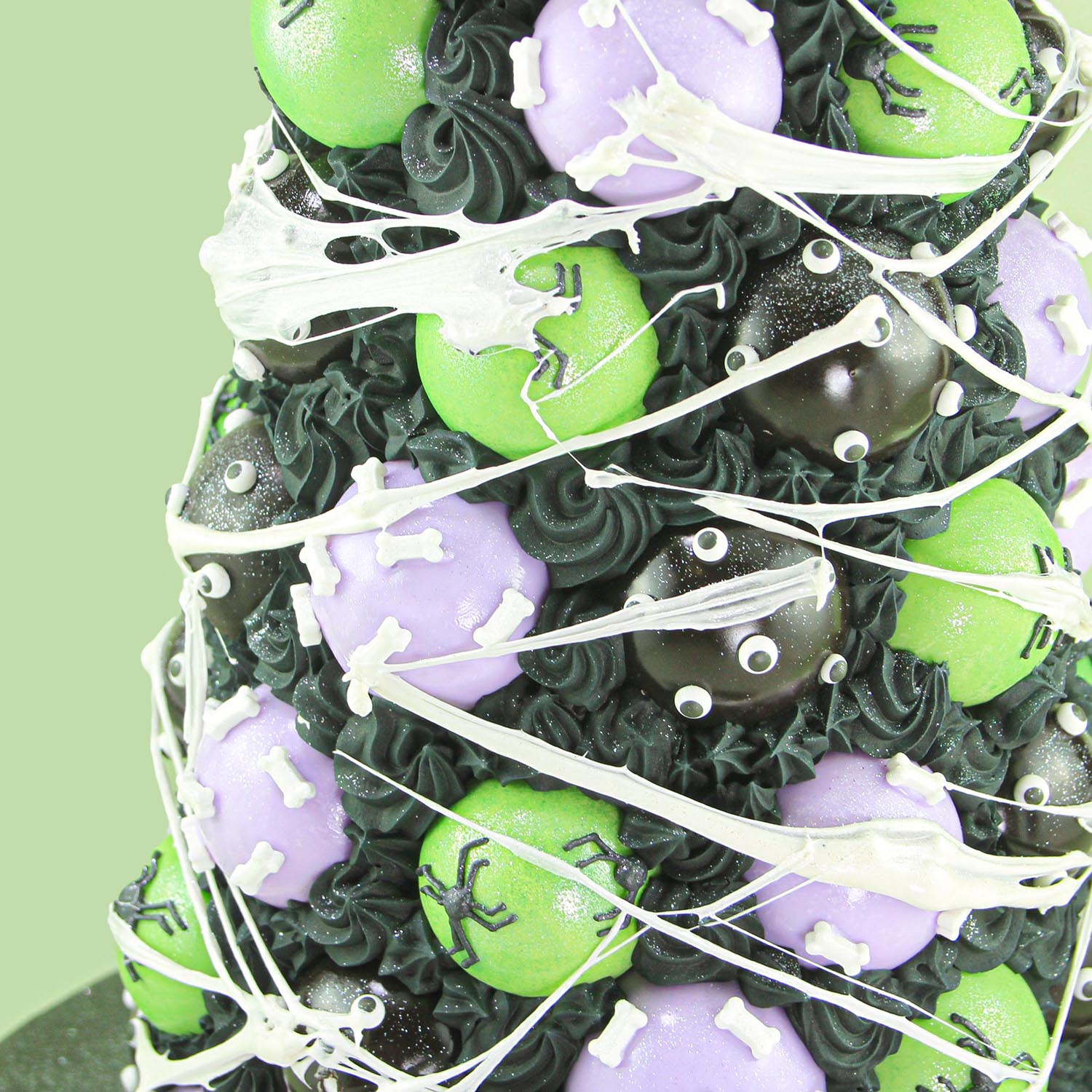 Black cake pops with eyes, green cake pops with hand piped spiders and purple cake pops adorned with candy bones.  Assembled on a cone tower and covered in a marshmallow spider web.