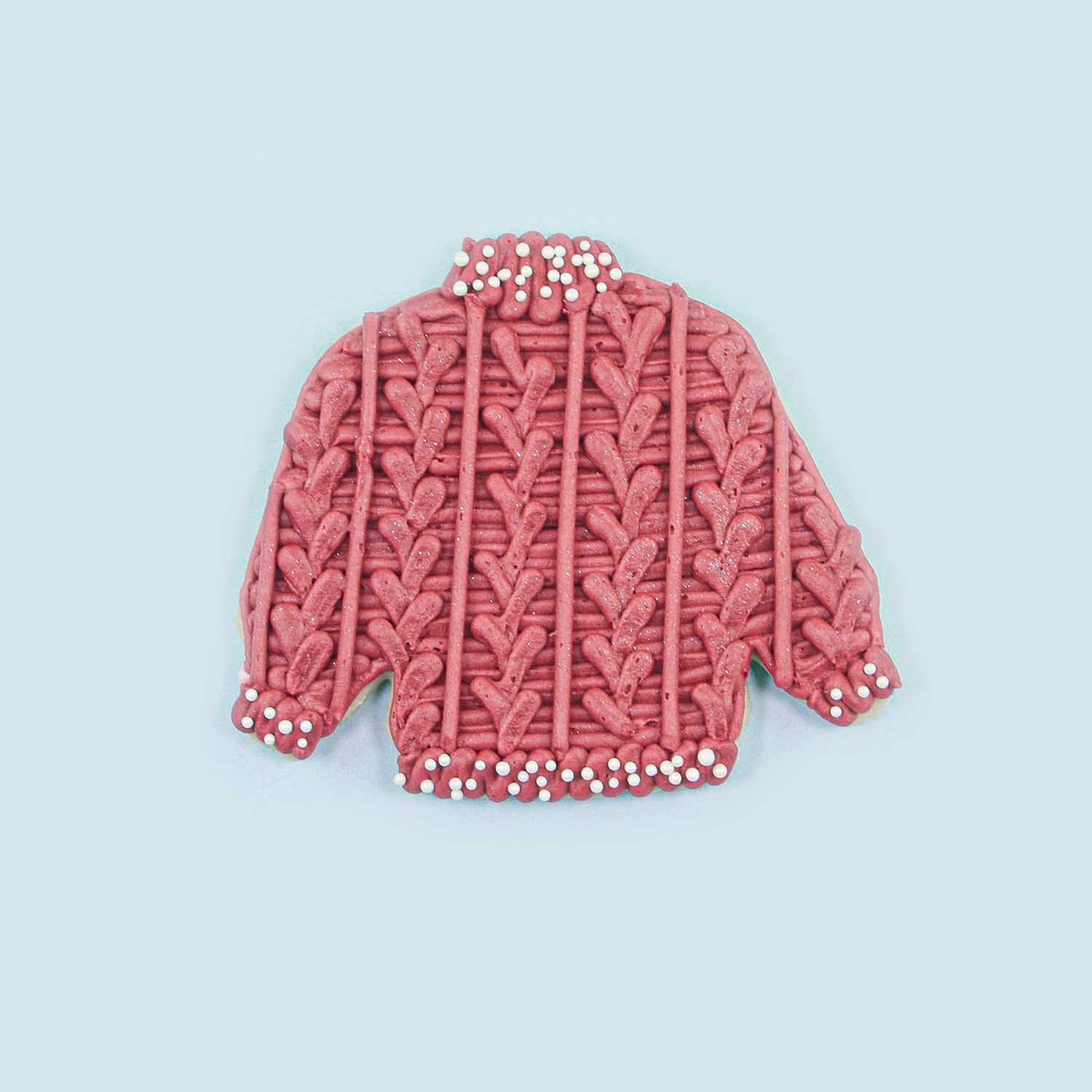 Red Cable Knit Sweater decorated in red buttercream and white nonpareils adorn the collar, hem and cuffs.