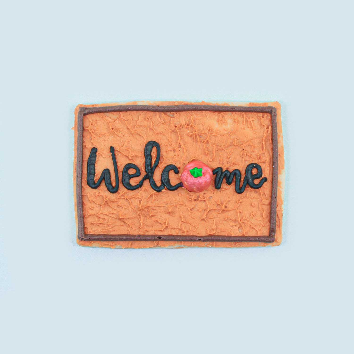 Rectangle cookie decorated in buttercream to look like a welcome mat at your front door.  Royal icing pumpkin takes place of the "o" in welcome.