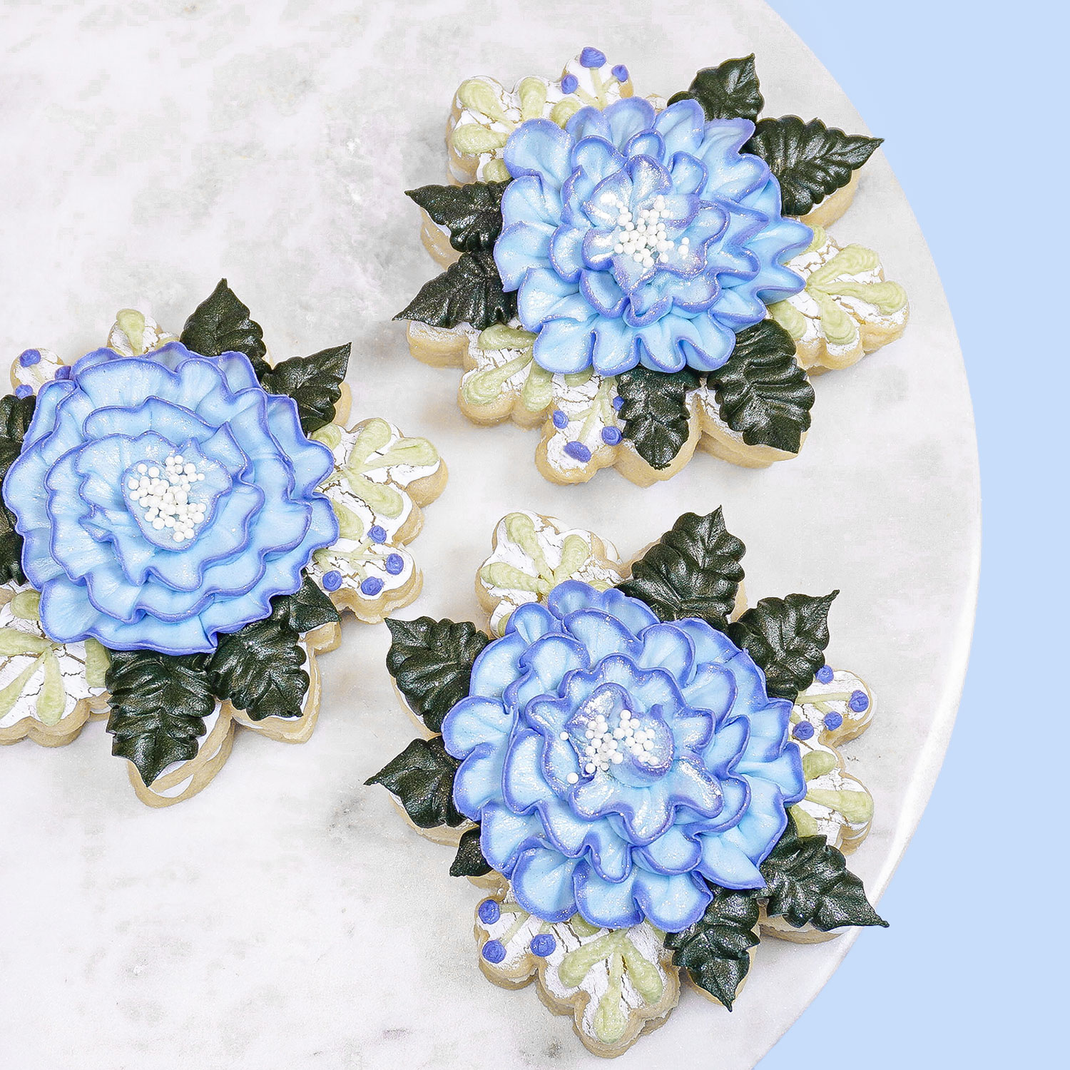 blue floral buttercream cookies on a marble platter