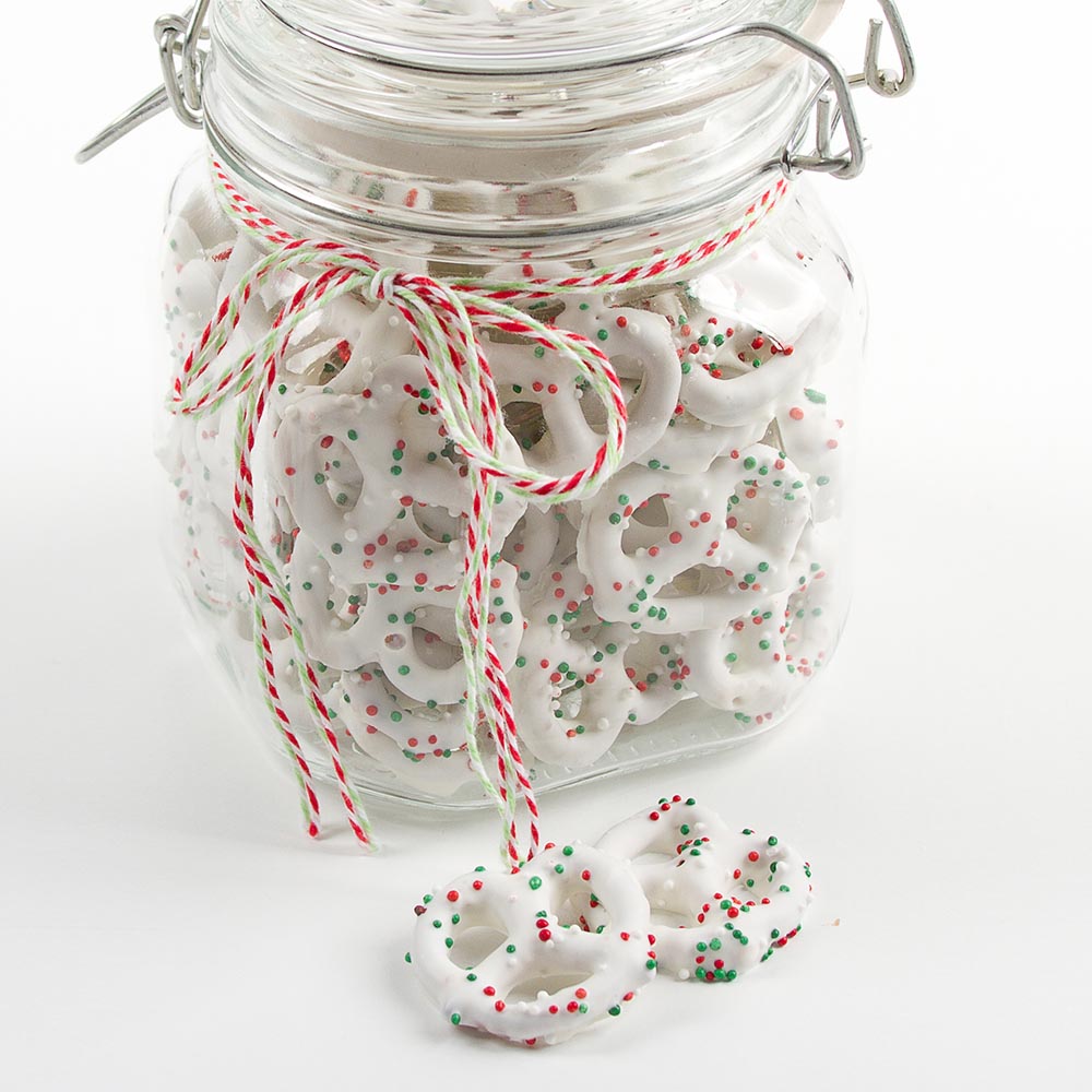 jar filled with mini white chocolate dipped pretzels sprinkled with red, green and white nonpareils