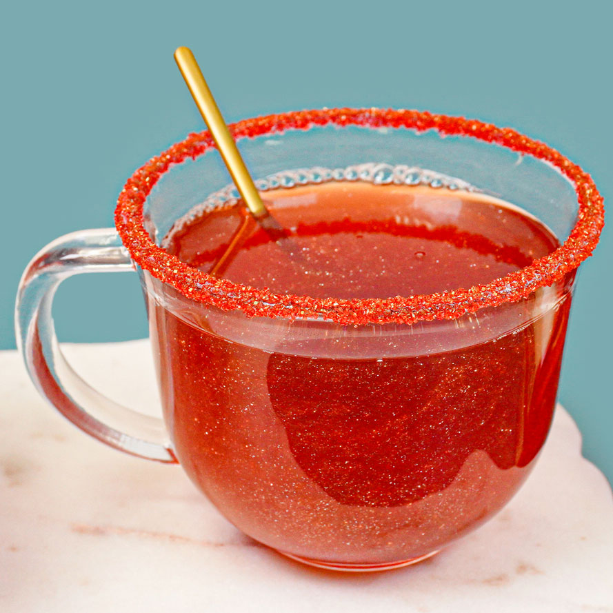 red glitter drink in clear mug with gold spoon