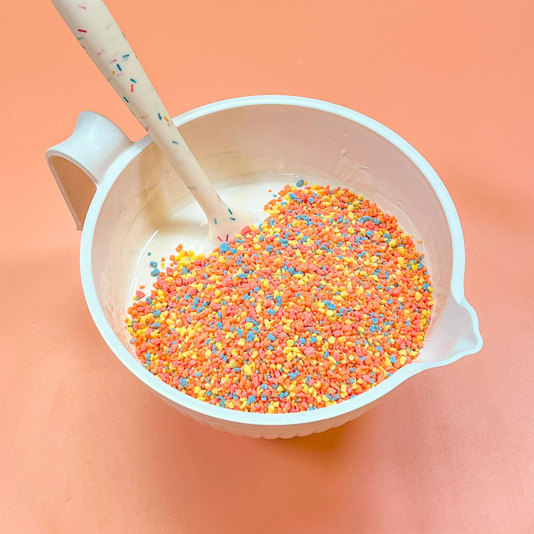 bowl with melted white chocolate with birthday cake candy crunch