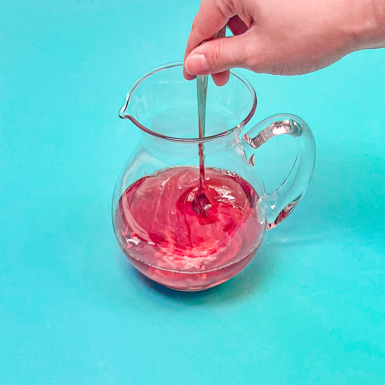 stirring cranberry juice with wilton white food coloring