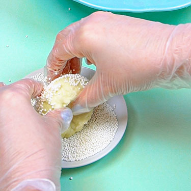 dipping cheeseball into white nonpareils