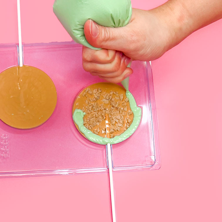 piping green apple chocolate into sucker mold