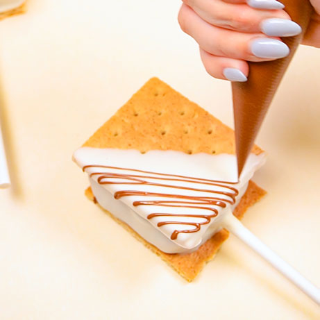 drizzling melted milk chocolate onto smores pop