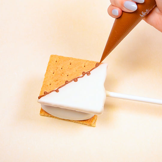 piping chocolate scrolls onto smores pop