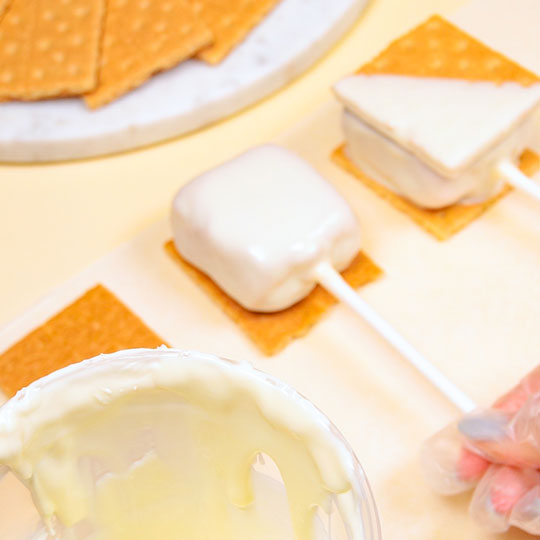 placing chocolate caramel covered marshmallow on graham cracker