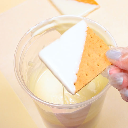 dipping graham cracker in melted white chocolate