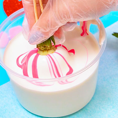 strawberry being dipped into pink marbled chocolate