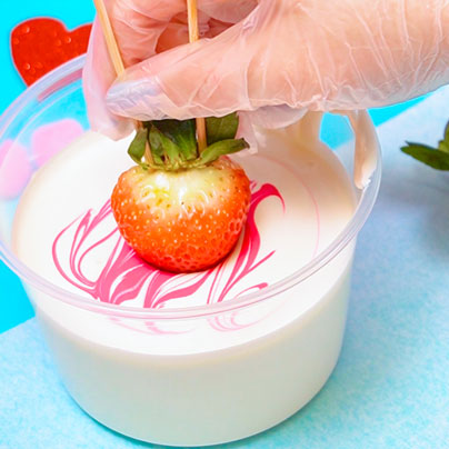 dipping strawberry into melted white chocolate