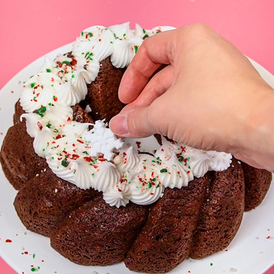 adding edible snowflakes onto a chocolate bundt cake