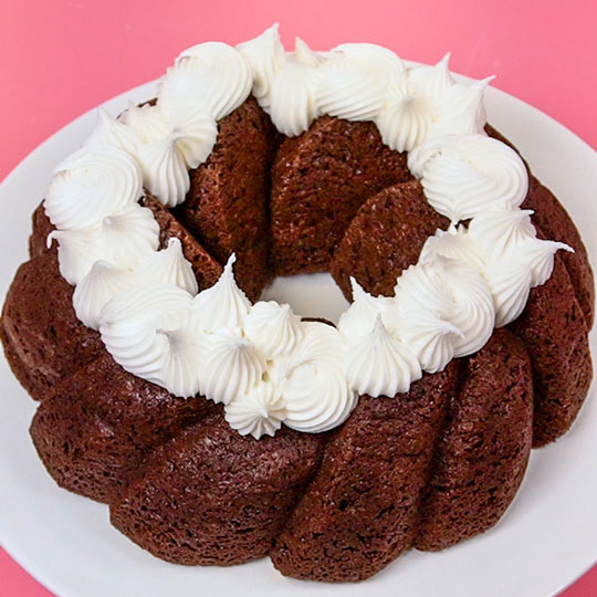 vanilla buttercream piped onto a chocolate bundt cake