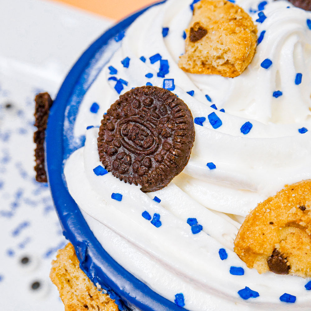 whipped cream piped onto hot chocolate with blue sprinkles and cookie pieces