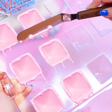 using an angled spatula to clean up the edges of the chocolate shells